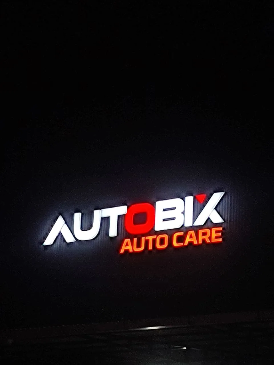 The illuminated AUTOBIX AUTO CARE sign at night