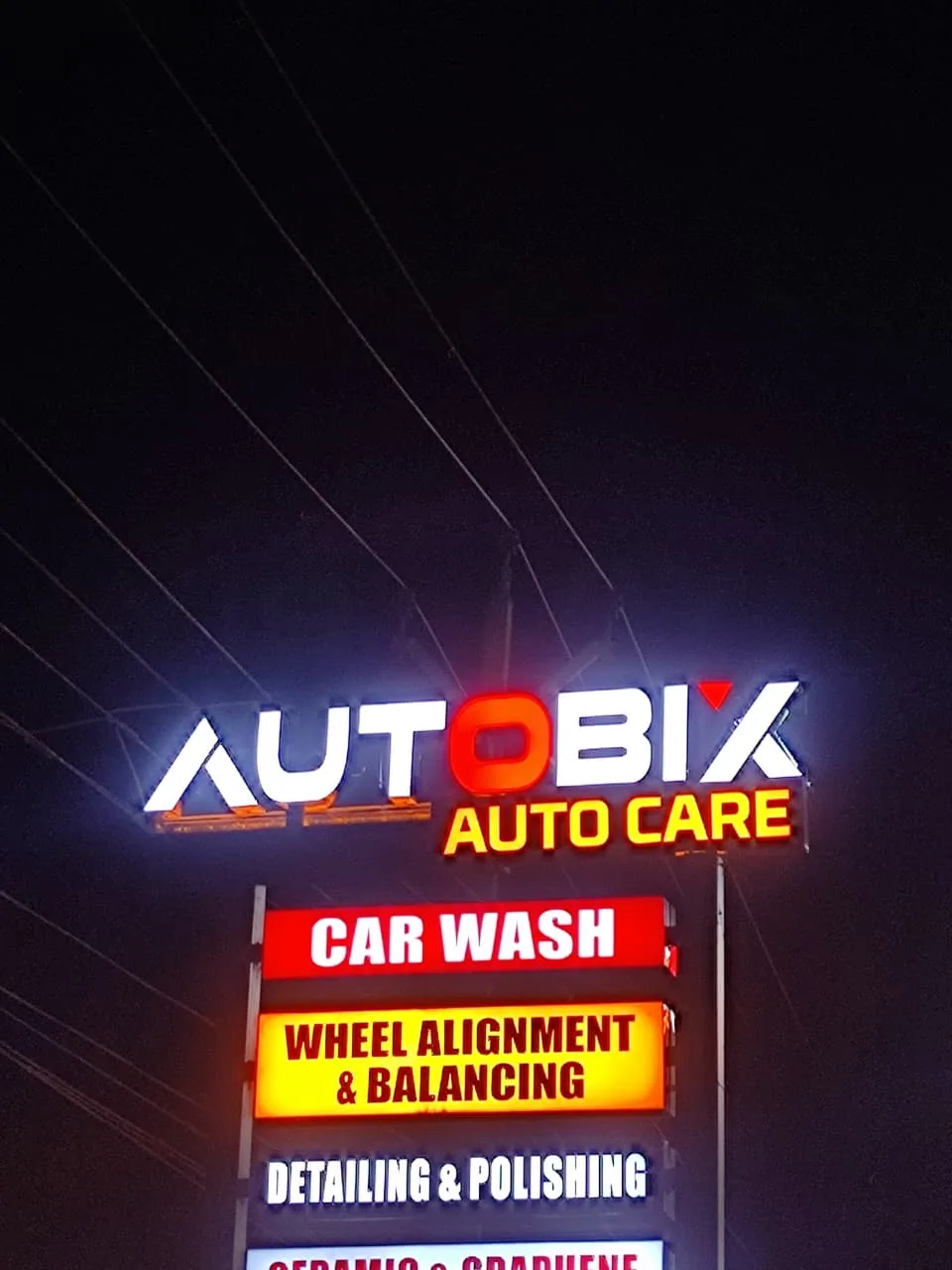 The illuminated AUTOBIX AUTO CARE sign glowing red and white at night