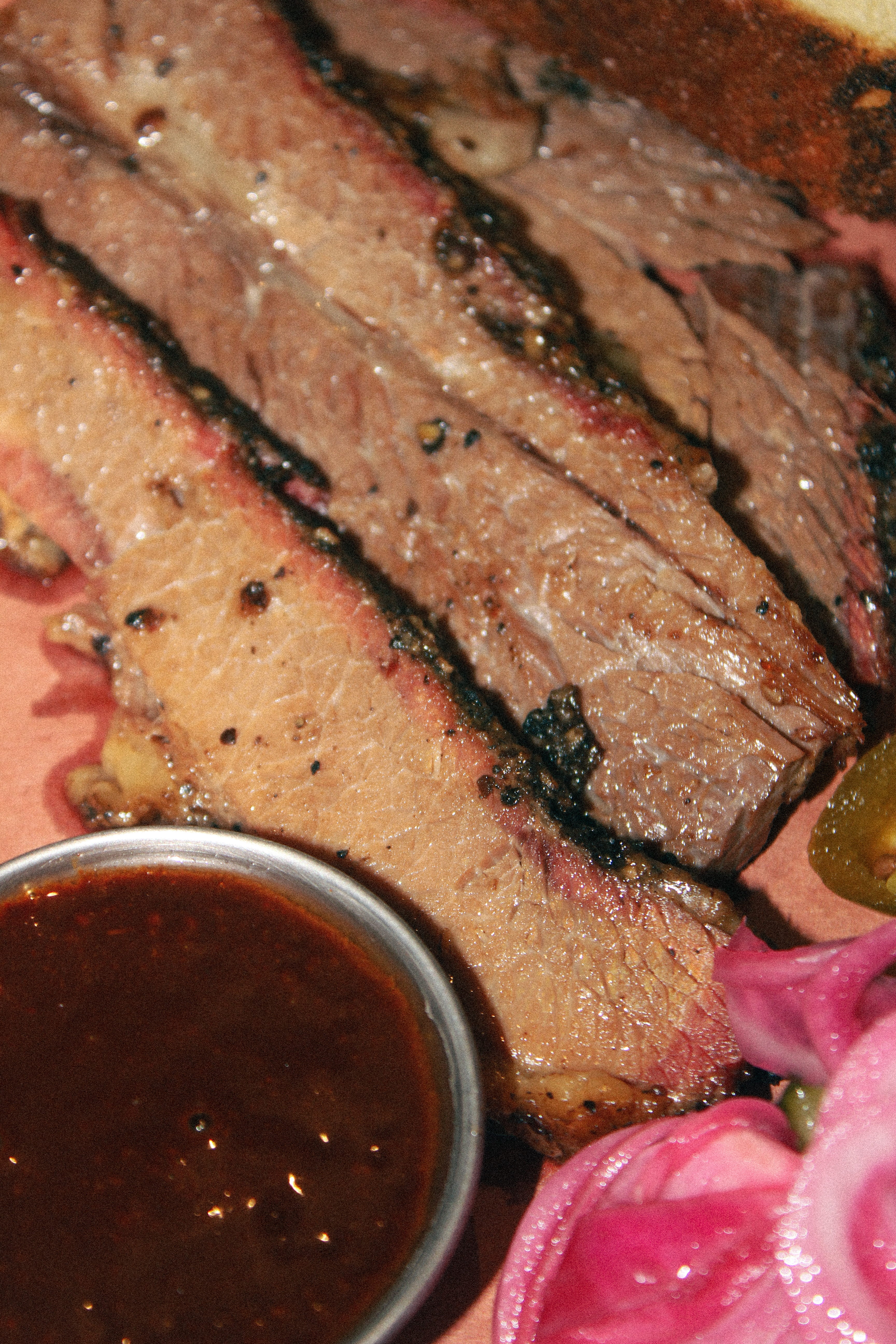 Smoked brisket sliced and served with sauce and pickled onions