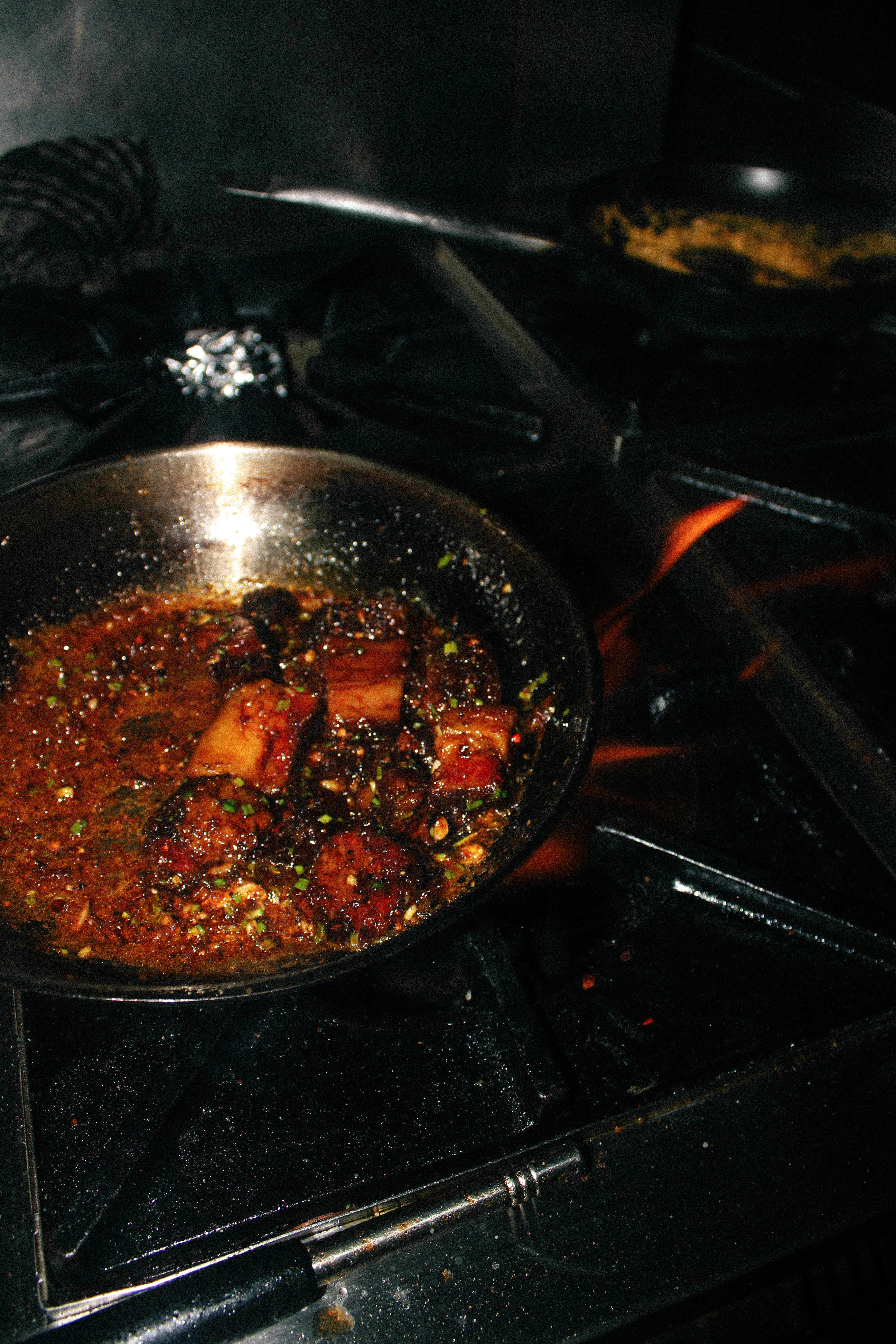 Meat glazing over an open flame in the kitchen